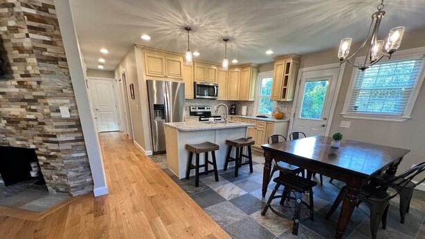 A spacious kitchen with a central island, wooden flooring, and a stone accent wall. - Beautiful Renovated Home Walk to University of Maine in Orono (Orono)