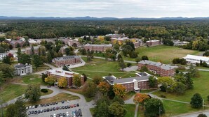 An aerial view of a campus with multiple red-brick buildings, green lawns, and a parking lot. - Beautiful Renovated Home Walk to University of Maine in Orono (Orono)