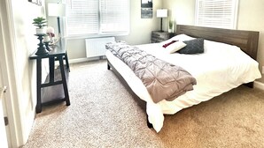 A bedroom with a bed, bedside tables, a lamp, a radiator, and a window with blinds. - Beautiful Renovated Home Walk to University of Maine in Orono (Orono)