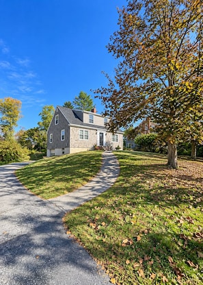 A two-story house with a stone facade, a front porch, and a driveway leading to the entrance.