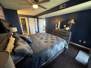 Quarto com cama, penteadeira e ventoinha no teto.