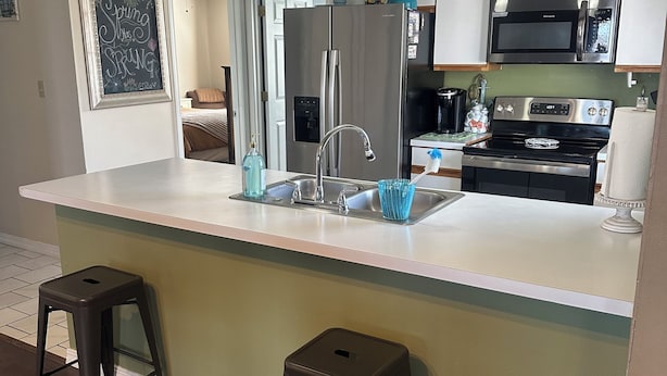 A kitchen with a central island, stainless steel appliances, and two bar stools. - Lake Ozark Condo- Come stay & play! (Lake Ozark)