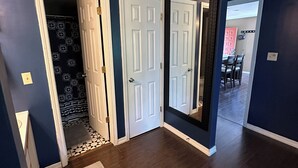 A hallway with a dark blue wall, a white door, and a mirror reflecting a dining area. - Lake Ozark Condo- Come stay & play! (Lake Ozark)