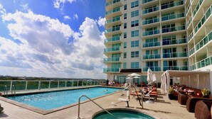 A rooftop pool area with a hot tub, lounge chairs, and a view of a high-rise building. - Coconut Grove 2/2.5 Apartment: Amazing Views Includes Parking (Miami)