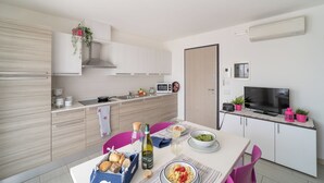 Una cocina moderna con armarios blancos, un microondas y un comedor con una mesa preparada para dos.