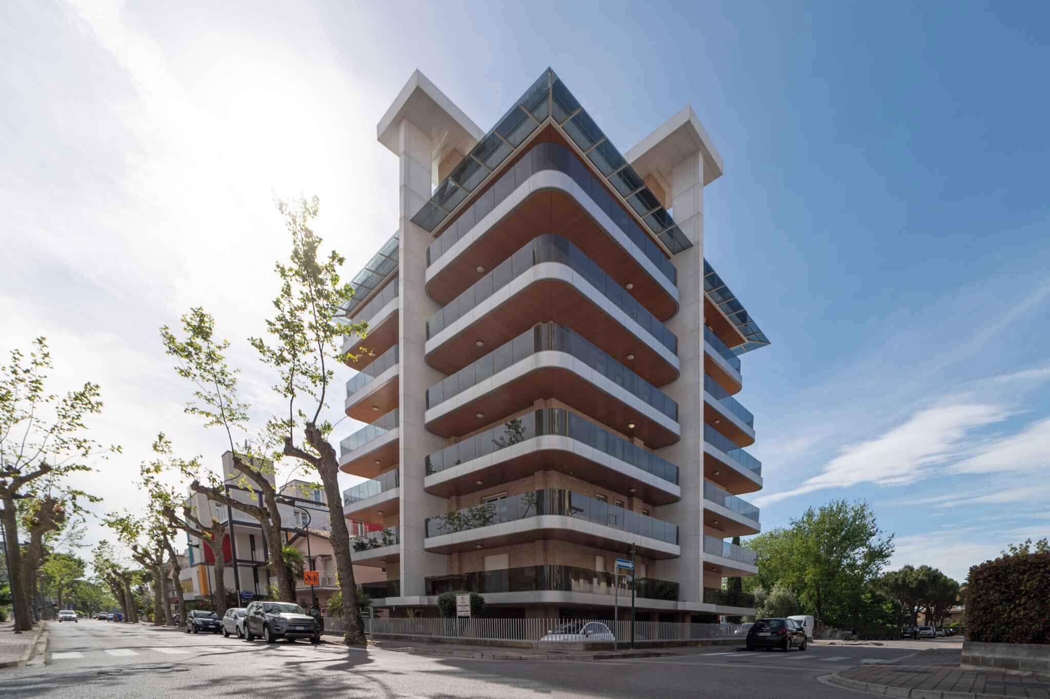 A multi-story building with a modern architectural design, featuring balconies and large windows.