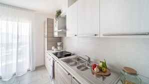 Una cocina moderna con armarios blancos, un lavamanos de acero inoxidable y una tabla de madera con verduras.
