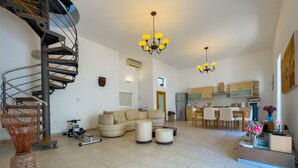A spacious living area with a modern staircase, a dining area, and a kitchen.