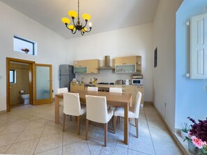 Een moderne keuken met een centraal eiland, houten kastjes en een eethoek met een tafel en stoelen.