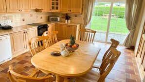 Een keuken met houten kastjes, een magnetron en een eettafel met stoelen.