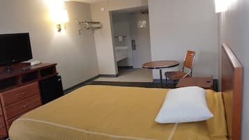 A hotel room with a bed, a TV, a desk, a chair, and a small table.