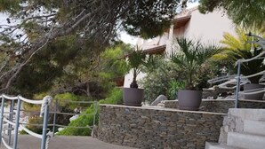 A stone wall with steps leading up to a building, surrounded by potted plants and trees. - Apartments Villa Marijana - Two Bedroom Apartment with Terrace and Sea View (Prižba)