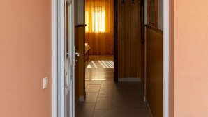 A hallway with a wooden door, a tiled floor, and a window with curtains. - Apartments Villa Marijana - Two Bedroom Apartment with Terrace and Sea View (Prižba)