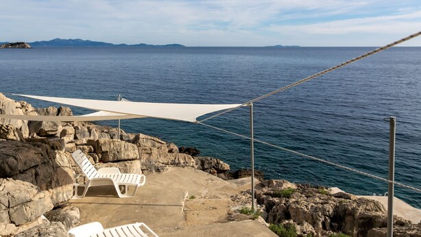 A coastal area with a rocky shoreline, a white canopy, and two white lounge chairs. - Apartments Villa Marijana - Two Bedroom Apartment with Terrace and Sea View (Prižba)