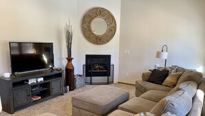 Una sala de estar con una televisión de pantalla plana, una chimenea, un sofá y un espejo decorativo.