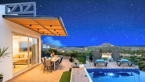 Une terrasse extérieure moderne, dotée d’une piscine, d’un espace salon et offrant une vue sur le paysage.