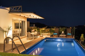 A modern outdoor pool area with a dining setup and a glass-enclosed space. - Canes Villa Heated Pool (Agios Nikolaos)
