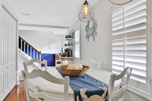 A dining area with a table set for four, featuring a woven basket and a blue table runner with a floral pattern.