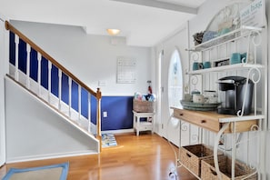 Enter a warm and inviting space with a welcoming sign above the door, a small table, and a shelf with a coffee maker.