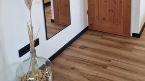 A hallway with a wooden floor, a large mirror, and a wooden door. - Studio "ton Barkenboom" (Esens)