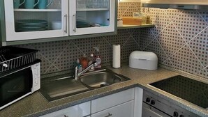 A kitchen with white cabinets, a microwave, a stove, and a sink. - Studio "ton Barkenboom" (Esens)