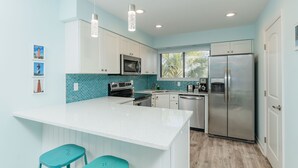 Een moderne keuken met witte kasten, een roestvrijstalen koelkast en turquoise accenten.