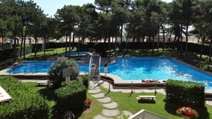A swimming pool area with two pools, surrounded by trees and greenery.