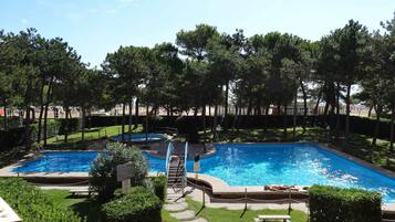 Un espace piscine comprenant deux piscines, entouré d’arbres et de verdure.