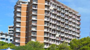 A multi-story residential building with balconies, a central vertical structure, and a clear sky.