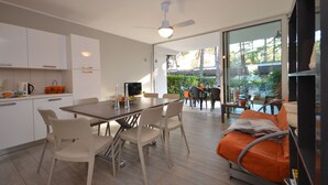 Une cuisine moderne avec des meubles blancs, une table à manger avec des chaises et un ventilateur de plafond.