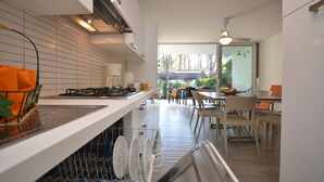 Une cuisine moderne avec des meubles blancs, un lave-vaisselle et un coin repas comprenant une table et des chaises.