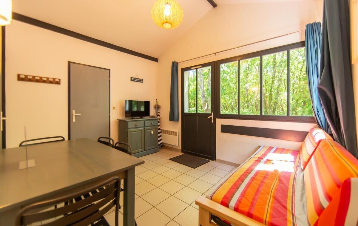 A room with a bed, a desk, a television, and a window with curtains.