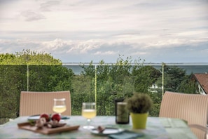 Ein Tisch mit Speisen und Getränken, mit Blick auf eine malerische Landschaft aus Bäumen und einem Gewässer.