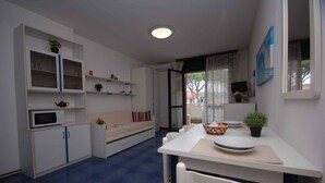 A compact kitchen with white cabinets, a microwave, and a dining area with a table and chairs.