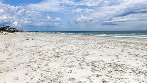 A wide sandy beach with a few buildings in the distance, under a partly cloudy sky. - Heaven Can Wait - Oceanfront w/ Heated Pool and Sooo Much More! (Garden City Beach)