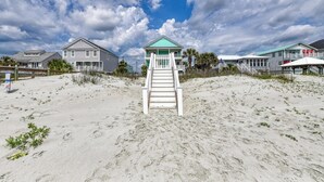A beachside hotel with a staircase leading to a covered area, surrounded by sand and vegetation. - Heaven Can Wait - Oceanfront w/ Heated Pool and Sooo Much More! (Garden City Beach)
