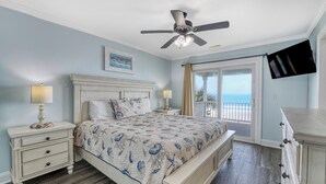 A bedroom with a bed, nightstands, a dresser, a ceiling fan, a painting, and a view of the ocean. - Heaven Can Wait - Oceanfront w/ Heated Pool and Sooo Much More! (Garden City Beach)