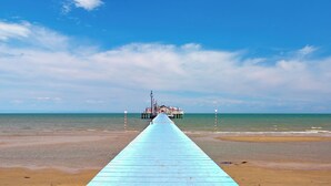 A pier extending into the sea with a building at the end.