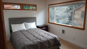 A bedroom with a bed, a nightstand, a window, and a view of the outdoors. - Mt. Pinos adjacent Mountain Cabin (Frazier Park)