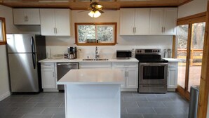 A modern kitchen with white cabinets, stainless steel appliances, and a central island. - Mt. Pinos adjacent Mountain Cabin (Frazier Park)