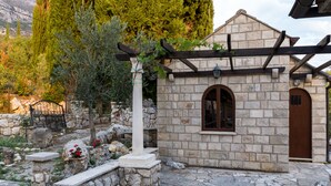 A stone building with a wooden pergola, a stone bench, and a stone wall with flowers. - Lazuština Paradise - Holiday Home with Swimming Pool (Gruda)