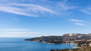 Une ville côtière offrant une vue dégagée sur la mer, avec une montagne en arrière-plan et une petite péninsule parsemée de bâtiments.