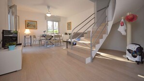 Una sala de estar moderna con una escalera, un comedor y una cocina.