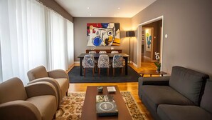 A modern living room with a sofa, a coffee table, and a dining area with chairs and a table. - "House of Joy" Apartment (Porto)