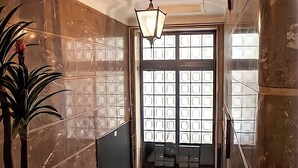 A hotel lobby with marble walls, a potted plant, a staircase, and a large window with a view. - "House of Joy" Apartment (Porto)