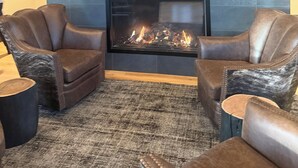 Una habitación con chimenea, sillones de cuero y cuernos de vaca colgados en la pared.