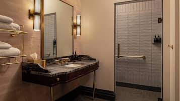 A modern bathroom with a marble sink, gold fixtures, and a glass shower enclosure.