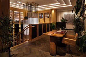 A modern interior with a wooden staircase, a desk with a chair, and potted plants. - Clayton Hotel & Members Club - Cherry Creek, Denver (Denver)