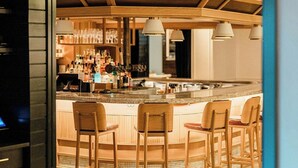 A bar area with wooden chairs and a bar counter, a tiled floor, and pendant lighting. - Clayton Hotel & Members Club - Cherry Creek, Denver (Denver)