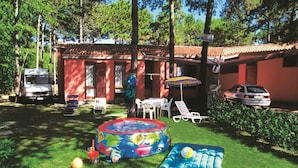 Un patio trasero con piscina, sillas de descanso y un coche aparcado cerca.